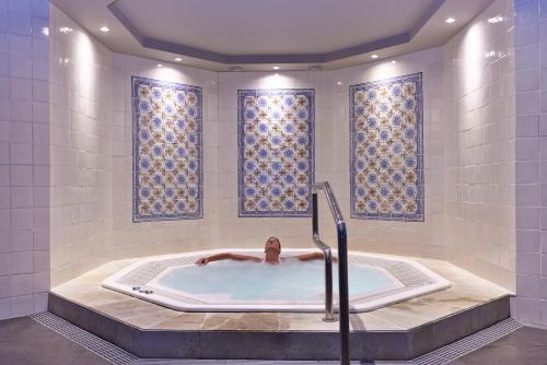 La salle de bains est pourvue d'une baignoire et de fenêtres. dans l'établissement The Cliff Bay - PortoBay, à Funchal