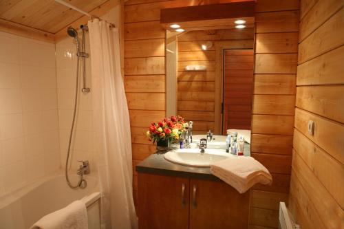 a bathroom with a sink and a shower and a tub at Résidence Néméa Les Chalets du Bois de Champelle in Morillon