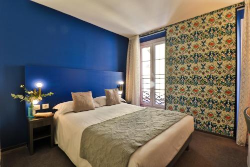 Dormitorio azul con cama y ventana en Hôtel Le G (ex Le Genève) en Niza