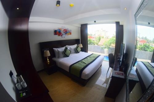a bedroom with a bed and a television in it at Ruvisha Beach Hotel in Negombo