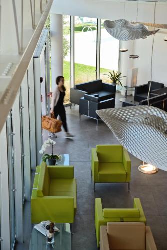 a person walking through a living room with green chairs at Best Western Hotel Rome Airport in Fiumicino