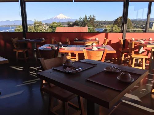 a restaurant with tables and chairs and a view of a mountain at Hotel Amun in Villarrica