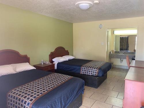 a hotel room with two beds and a bathroom at Texas Inn Beaumont in Beaumont