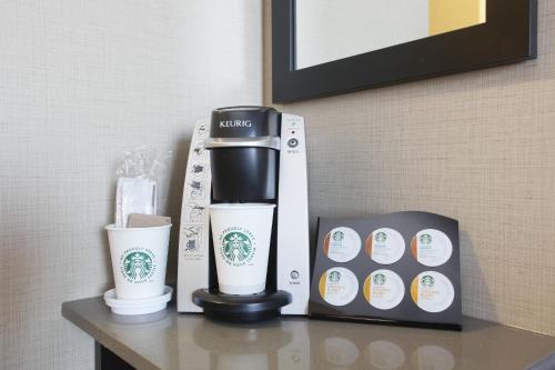 a coffee maker and two cups on a table at Pomeroy Hotel Fort McMurray in Fort McMurray