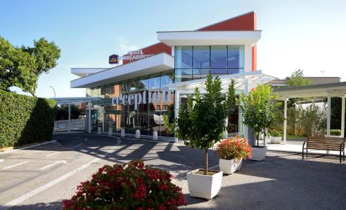 a large white building with plants in front of it at Best Western Hotel Rome Airport in Fiumicino