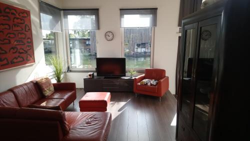 a living room with a couch and two chairs and a tv at Houseboat Vliegenbos in Amsterdam