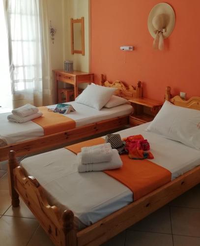 two beds in a room with orange walls at Ionio Sea Poros Studios in Mikros Gialos