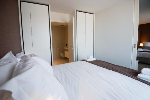 a bedroom with a large white bed with a mirror at Acropolis - Luxury Appartments I Hotelservice and parking in Middelkerke