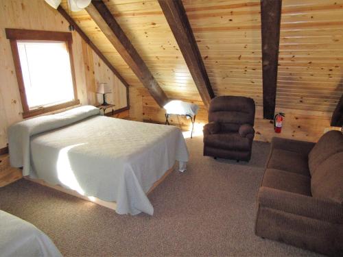a bedroom with a bed and a chair in a cabin at Freedom Ridge Cabins in Hill City