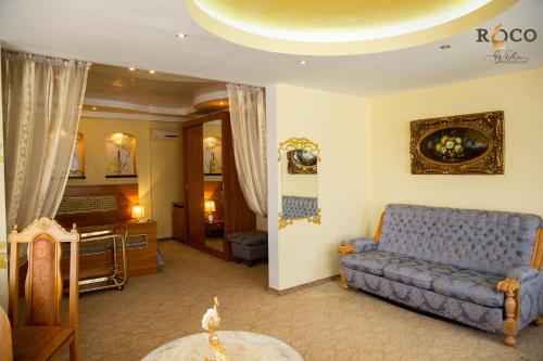 a living room with a blue couch and a table at Hotel Roco in Izvin