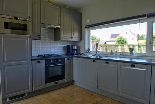 eine Küche mit weißen Schränken, einem Waschbecken und einem Fenster in der Unterkunft Holiday Home Garnaalhuisje in Oostduinkerke