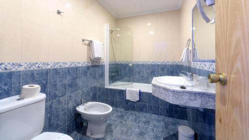 W wyłożonej niebieskimi kafelkami łazience znajduje się toaleta i umywalka. w obiekcie Vivero Playa w mieście Suances