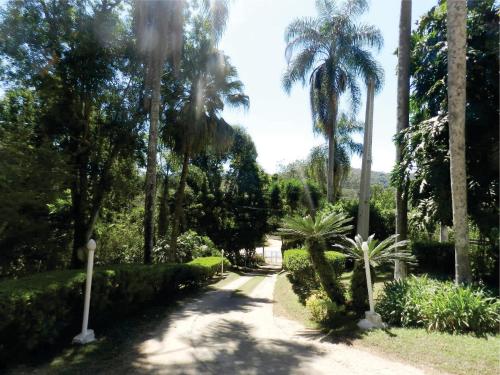 a garden with palm trees and a dirt road at Hotel Fazenda Bandeirantes in Ibiúna