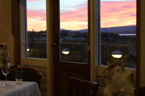 a table with a view of a sunset from a window at Hótel Eyvindará in Egilsstadir