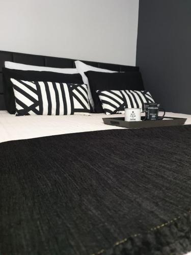 a bed with black and white pillows and a tray on it at Volos Center Luxury Home in Volos