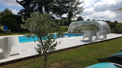 een zwembad met een prieel en een tafel en stoelen bij Manoir des Turets in Yvré-lʼÉvêque