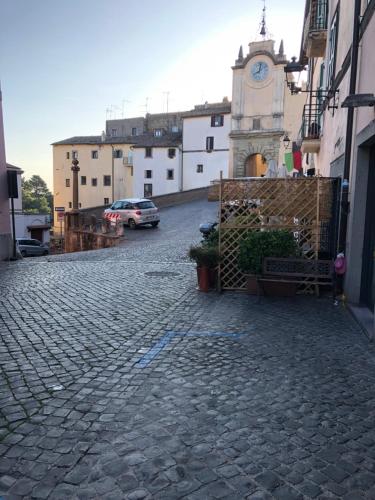 a cobblestone street with a clock tower in a town at Le case di Nonna Gina in Capranica