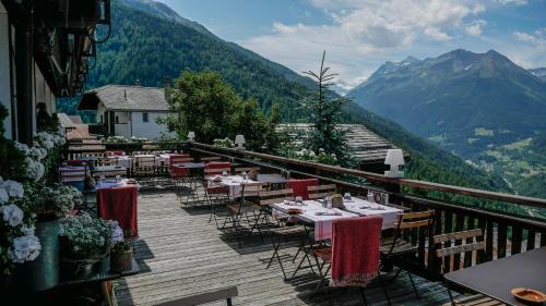 a restaurant with tables and chairs on a balcony with mountains at Hôtel Le Grand Chalet Favre in Saint-Luc