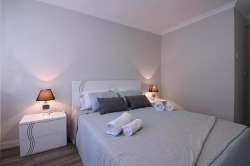 a white bedroom with a large bed with two lamps at Casa Cervo Artes in Vila Nova de Cerveira