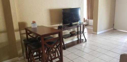 a living room with a television and a table and chairs at Days Inn by Wyndham Cocoa Cruiseport West At I-95/524 in Cocoa