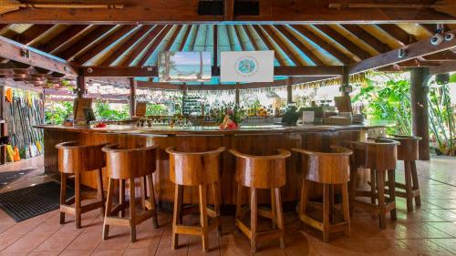 a bar in a restaurant with wooden stools at Sanctuary Rarotonga on the Beach (Adults Only) in Rarotonga
