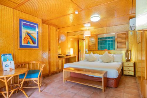 1 dormitorio con 1 cama, mesa y silla en Sanctuary Rarotonga on the Beach (Adults Only) en Rarotonga