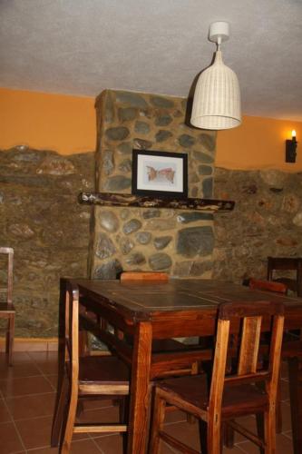 a dining room table with chairs and a stone wall at Casa Do Quelho in Janeiro de Cima