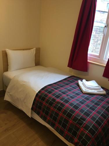een slaapkamer met een bed met een geruite deken en een raam bij 15 New Row in Londen