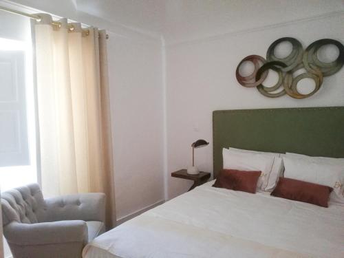 a bedroom with a bed and a chair and a window at Casa Brazao Mira in Casa Branca