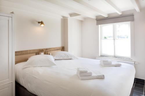 1 dormitorio con 1 cama blanca y 2 toallas en Cottage de Vinck, en Ypres