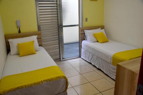 - 2 lits dans une petite chambre avec fenêtre dans l'établissement Pousada Tokyo Plaza, à Mogi das Cruzes