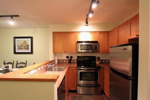 a kitchen with wooden cabinets and stainless steel appliances at Glacier's Reach by Whistler Retreats in Whistler