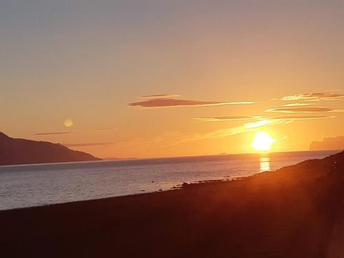 a sunset on the beach with the sun setting at Lyngen Vista - Arctic Luxury in Hamnnes