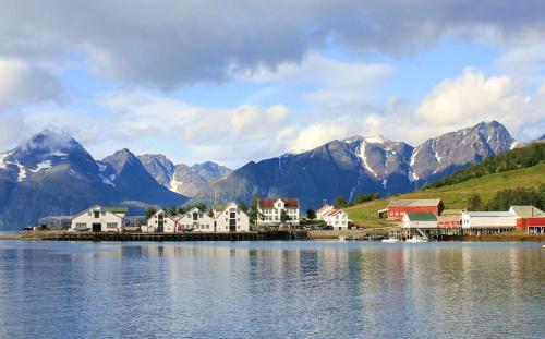 a town on the shore of a body of water with mountains at Lyngen Vista - Arctic Luxury in Hamnnes
