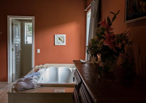 a bathroom with a sink and a vase of flowers on a counter at Pousada Quinta dos Pássaros Itaipava in Itaipava