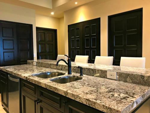 a kitchen with two sinks and a counter with chairs at Cabo Cottage Copala · Stunning * Luxury Ocean View 2BR*Resort Living in Cabo San Lucas