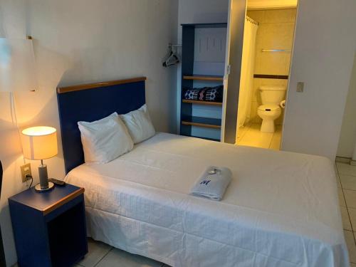 1 dormitorio con 1 cama blanca grande y baño en Hotel H Montreal en Guadalajara