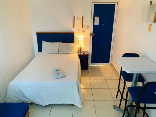 1 dormitorio con 1 cama blanca, mesa y sillas en Hotel H Montreal en Guadalajara
