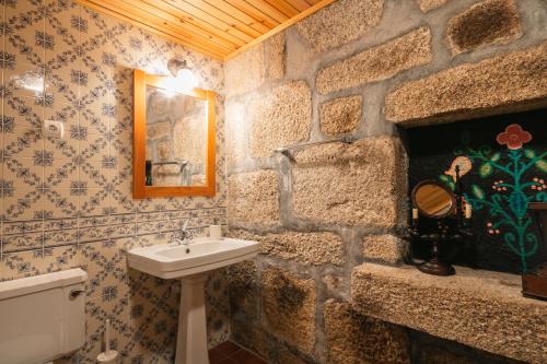 ein Badezimmer mit einem Waschbecken und einer Steinmauer in der Unterkunft Torrinheira ~ Family Pool Villa and Woods in Travanca