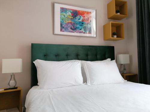 a bed with a green headboard and white pillows at Temple Suites Guesthouse in Portimão