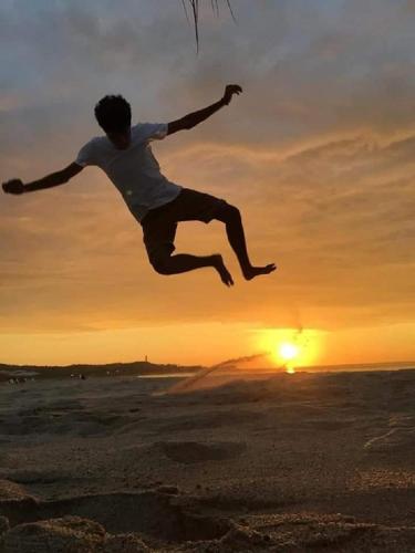 a man jumping in the air on the beach at sunset at Las palmeras de bocapan in Tumbes