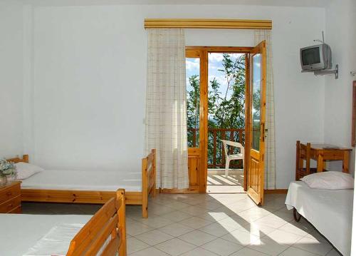 a bedroom with two beds and a balcony with a tv at Studios Thanasis in Limenaria