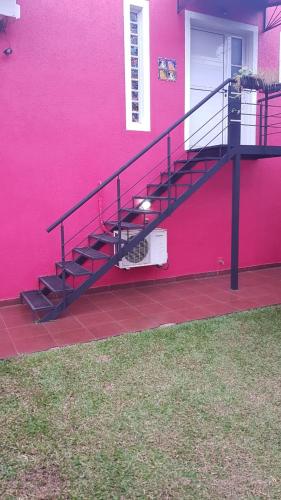 a pink building with a staircase next to a door at Casa 24 Puerto Iguazu in Puerto Iguazú