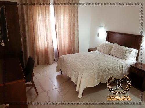 1 dormitorio con 1 cama con cabecero de madera en Hotel Real Victoria, en Tepatitlán de Morelos