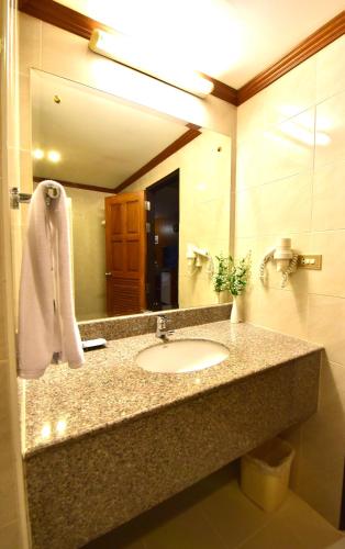 a bathroom with a sink and a large mirror at Dynasty Inn Pattaya in Pattaya