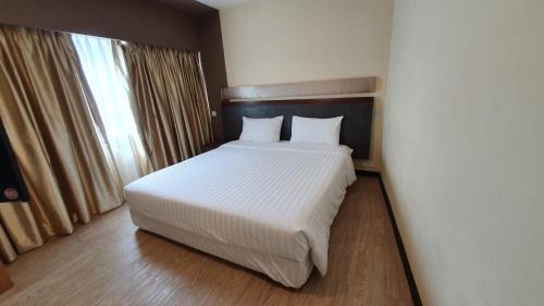 a bedroom with a bed with white sheets and a window at The Capital Residence Suites in Bandar Seri Begawan