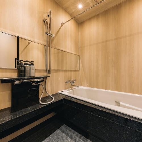 a bathroom with a bath tub and a mirror at Hotel Yururito Osaka in Osaka