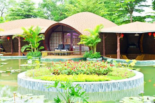 a garden with a building and a pond with flowers at Con Khuong Resort Can Tho in Can Tho