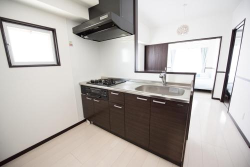 uma cozinha com armários castanhos e um lavatório em EX Itoman Apartment 401 em Itoman