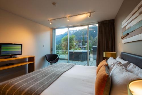 a hotel room with a bed and a large window at Kent Street Apartments - Element Escapes in Queenstown